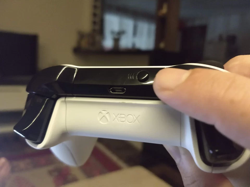 Foto em close mostrando a localização do botão de emparelhamento (botão sync) no topo de um controle de Xbox One S branco.