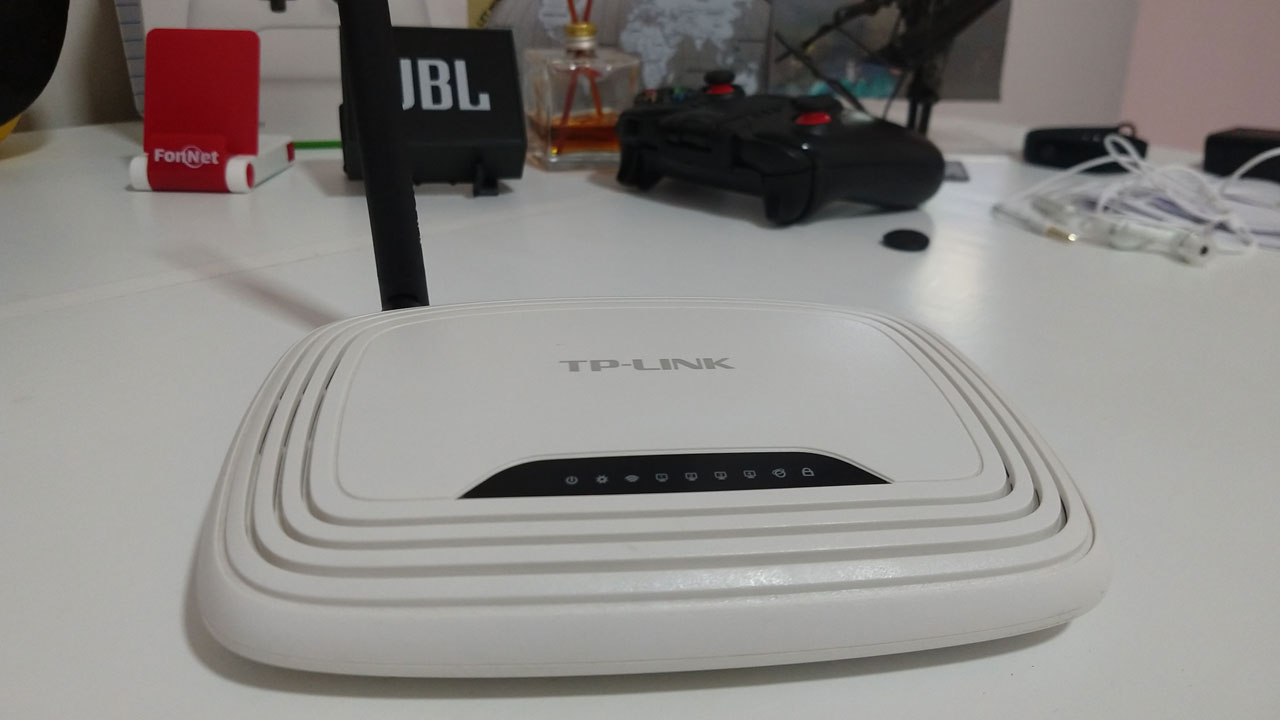 Roteador Wi-Fi branco da marca TP-Link posicionado sobre uma mesa branca com antenas levantadas.
