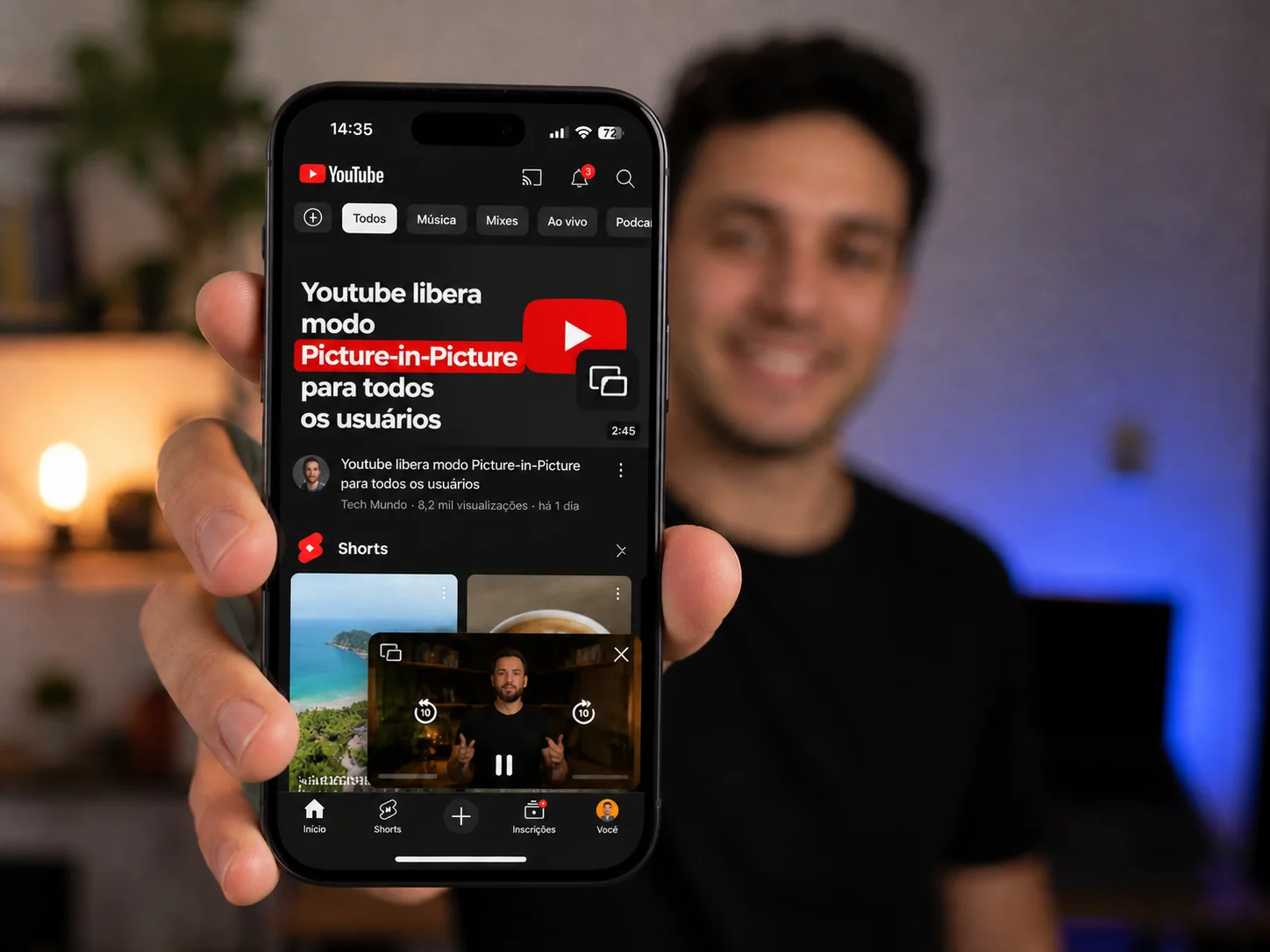 Homem segurando um smartphone que exibe um vídeo do YouTube funcionando no modo Picture-in-Picture (janela flutuante) sobre a tela inicial.