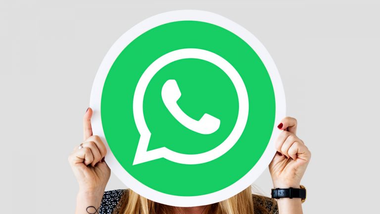 Imagem mostra uma mulher loira segurando a logo do WhatsApp em frente ao seu rosto.