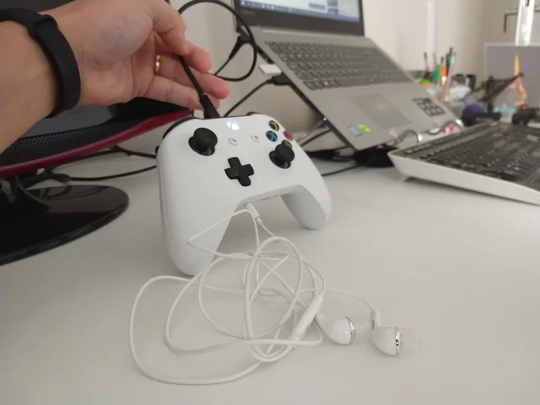 Foto aproximada de um controle de Xbox One S branco sendo conectado a um computador através de um cabo USB para atualização de firmware.