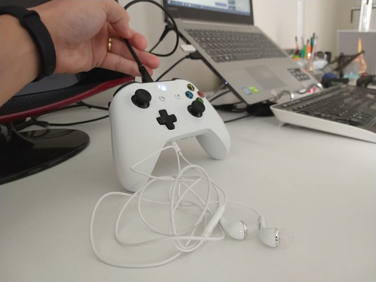 Foto aproximada de um controle de Xbox One S branco sendo conectado a um computador através de um cabo USB para atualização de firmware.