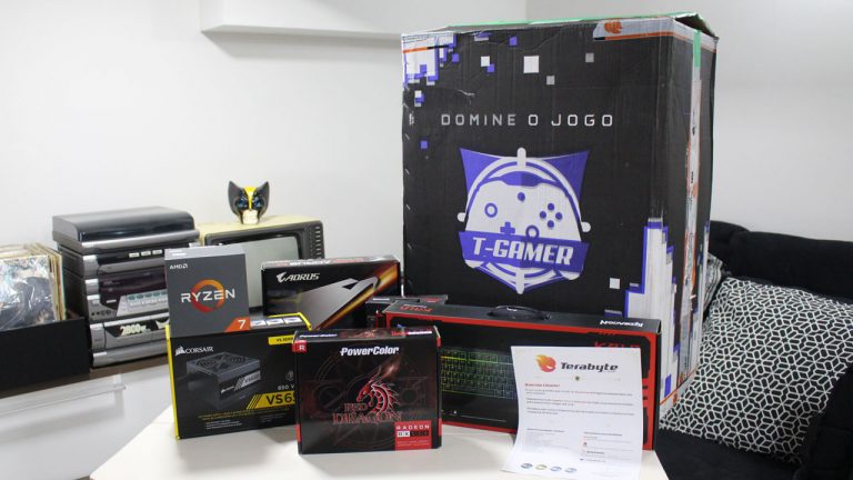 Foto de unboxing de PC Gamer da Terabyte Shop mostrando caixas de componentes como processador AMD Ryzen, placa-mãe Aorus, memórias G.Skill e gabinete Corsair sobre uma mesa.