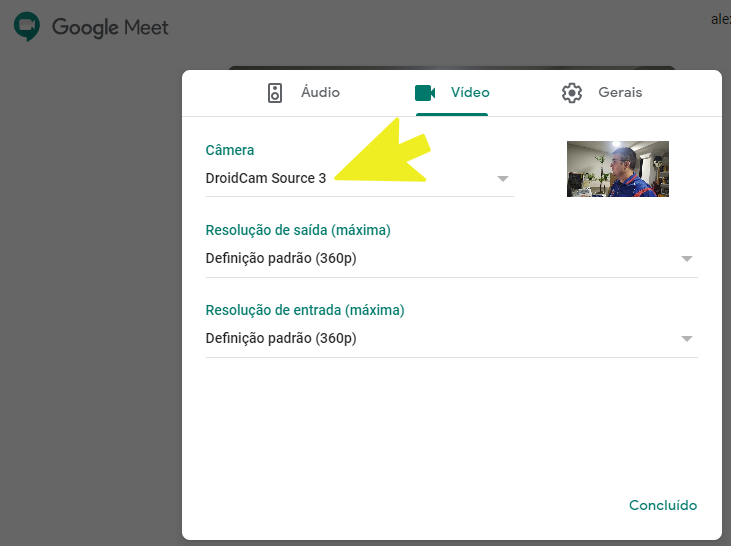 Interface de configurações do Google Meet em um computador, com uma seta amarela apontando para a seleção da câmera "DroidCam Source 3".