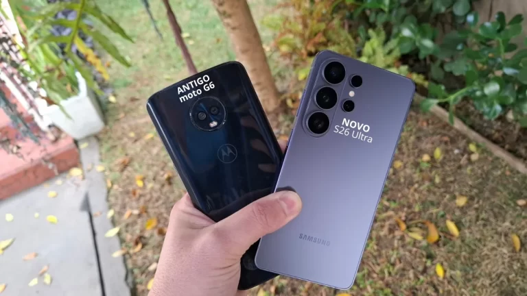 Foto de uma mão segurando dois smartphones Android, um azul escuro (moto G6 Plus) e um violeta (S26 Ultra), ao ar livre, ilustrando o momento de preparação para a venda do aparelho antigo.