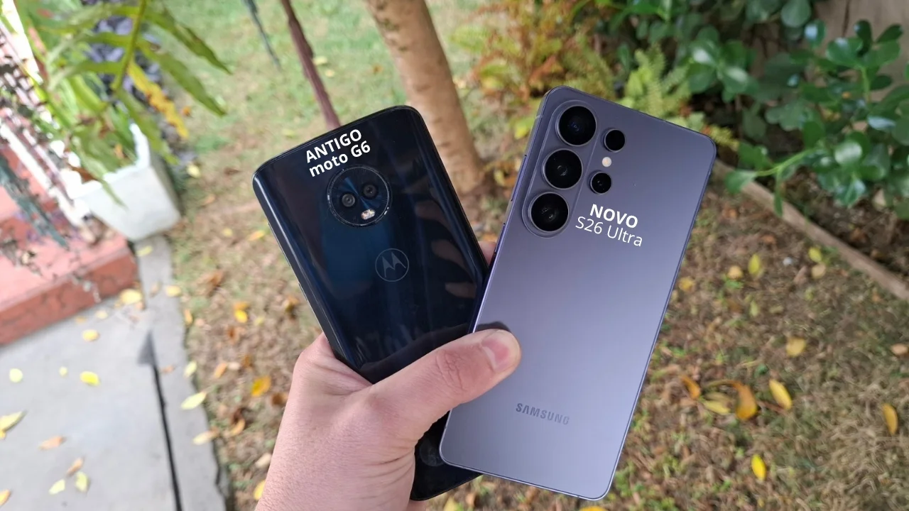 Foto de uma mão segurando dois smartphones Android, um azul escuro (moto G6 Plus) e um violeta (S26 Ultra), ao ar livre, ilustrando o momento de preparação para a venda do aparelho antigo.