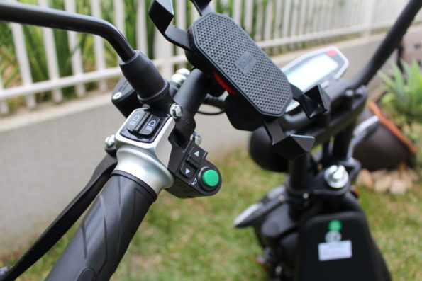 Detalhe do guidão da scooter com suporte para celular e manoplas.
