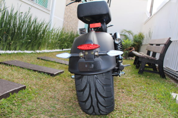 Ângulo traseiro inferior da scooter destacando o pneu largo e a suspensão.