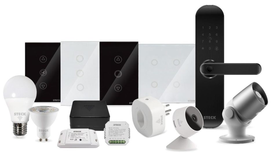 Exibição de diversos produtos da linha Smarteck da Steck sobre um fundo branco, incluindo lâmpadas LED inteligentes, interruptores touch, mini-interruptor interno, controle universal infravermelho e câmeras de segurança Wi-Fi.