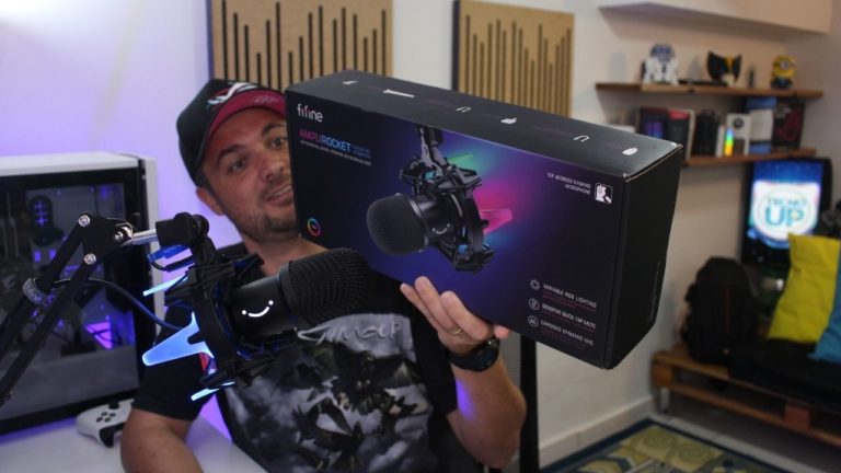Alexandre segurando a caixa do microfone dinâmico FIFINE AmpliRocket K651 durante o vídeo de unboxing.
