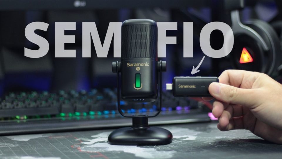 Microfone Saramonic SR-MV2000W em cima de uma mesa, com o transmissor wirelless sendo segurado por uma mão.