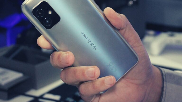Visão traseira do smartphone Asus Zenfone 8 sendo segurado por uma mão, destacando o design compacto e as câmeras.