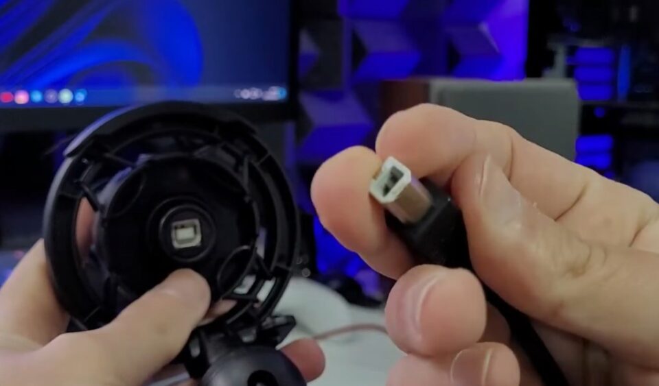 Mão segurando o cabo de conexão USB Tipo B (estilo impressora) do microfone DT3 BYT.