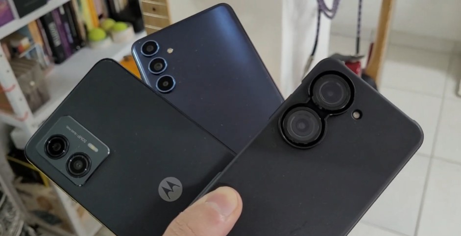 Close em três smartphones diferentes sendo segurados pela mão, destacando as lentes das câmeras traseiras para exemplificar o uso de HDR.