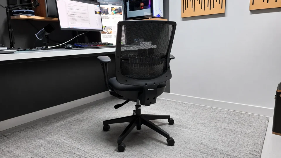 Cadeira de escritório Flexform Uni All Black posicionada em um home office com piso cinza e mesa branca ao fundo.
