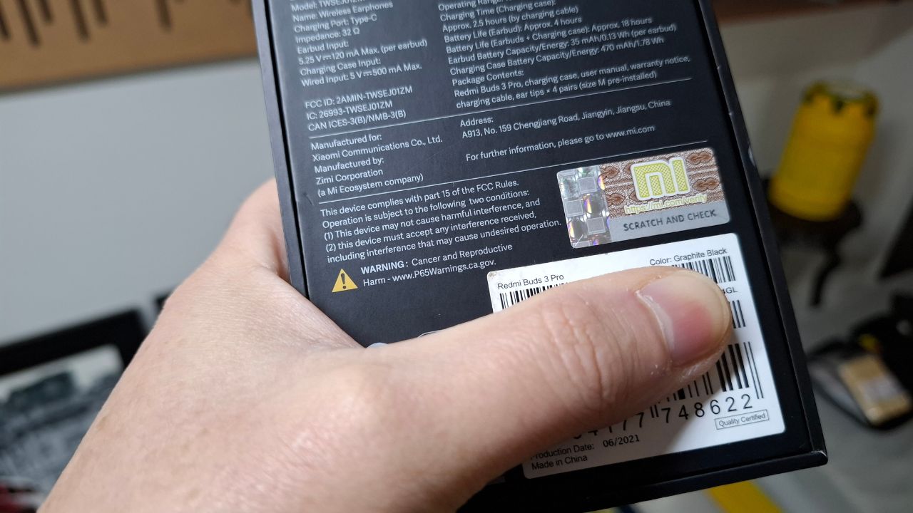 Foto detalhada da traseira da caixa do fone Redmi Buds 3 Pro mostrando o aviso amarelo 'WARNING: Cancer and Reproductive Harm' seguido do site P65Warnings.ca.gov.