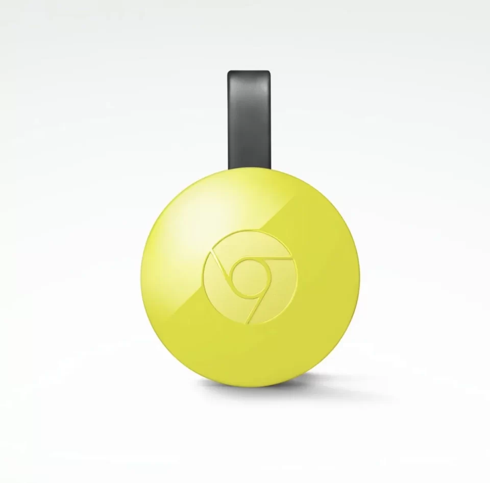 Visão frontal do Google Chromecast de 2ª geração na cor amarela, com seu formato circular característico e fundo branco.