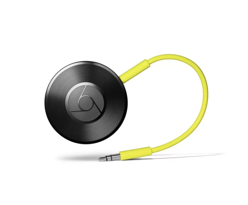 Visão superior do aparelho circular Chromecast Audio na cor preta, com ranhuras que imitam um disco de vinil, conectado a um cabo auxiliar amarelo.