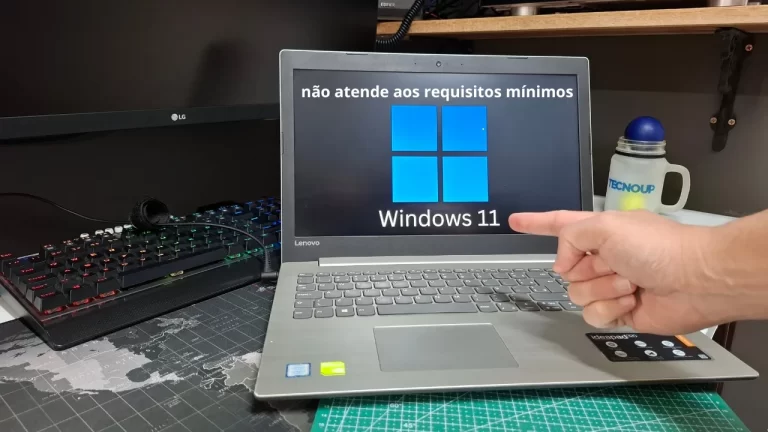 Close em uma mão apontando para a tela de um notebook exibindo a mensagem de erro "não atende aos requisitos mínimos" para o Windows 11.