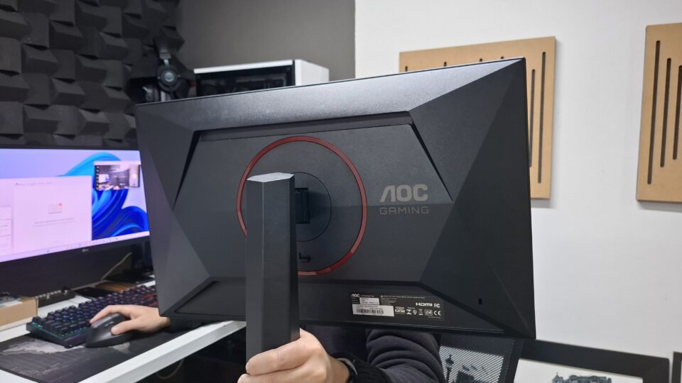 Foto da parte traseira do monitor AOC Gaming G4 24G4/P, destacando o design com detalhes em vermelho e a base robusta com ajuste de altura.