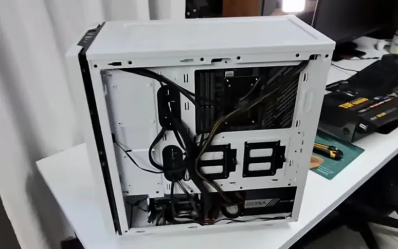 Vista interna lateral de um gabinete de PC branco com os cabos organizados e presos com fitas na parte traseira.