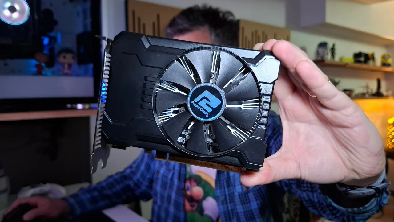 Alexandre do TecnoUp segurando uma placa de vídeo AMD Radeon RX 550 preta, demonstrando como preparar o hardware para uma limpeza completa de drivers.
