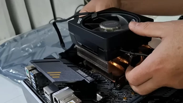 Close-up de mãos realizando a montagem cuidadosa de um computador gamer, instalando um air cooler sobre a placa-mãe em uma bancada de hardware.