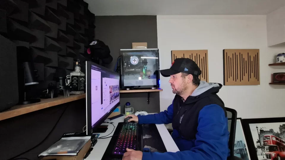 Fotografia de Alexandre Cordeiro, editor e fundador do portal TecnoUp, sentado em frente a uma mesa com monitor duplo e equipamentos de hardware e iluminação de estúdio.
