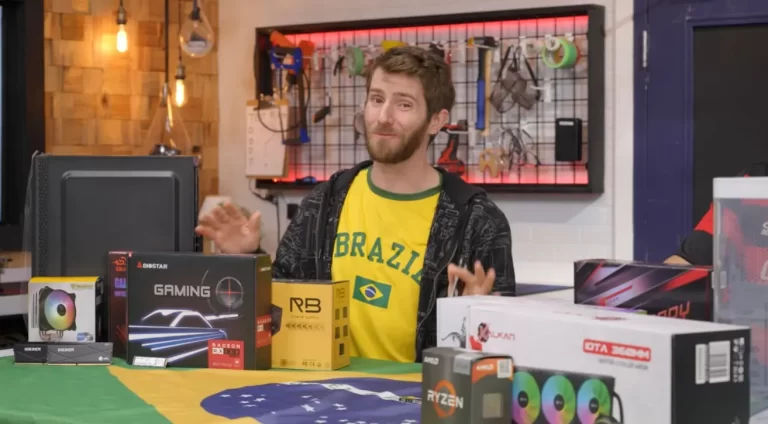 Linus Sebastian, do canal Linus Tech Tips, vestindo uma camiseta do Brasil e cercado por caixas de hardware durante o vídeo sobre o custo de montar um PC no país.