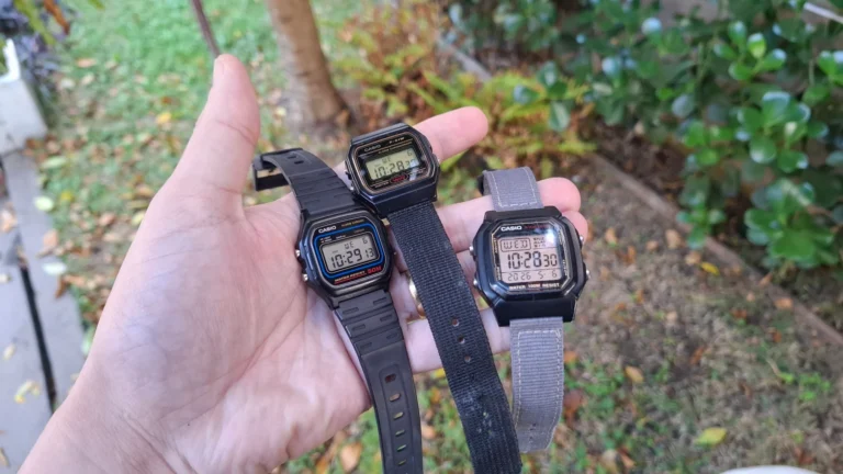 Close das mãos de Alexandre segurando três modelos de relógio Casio: o clássico F-91W, o resistente W-59 e o robusto W-800H.
