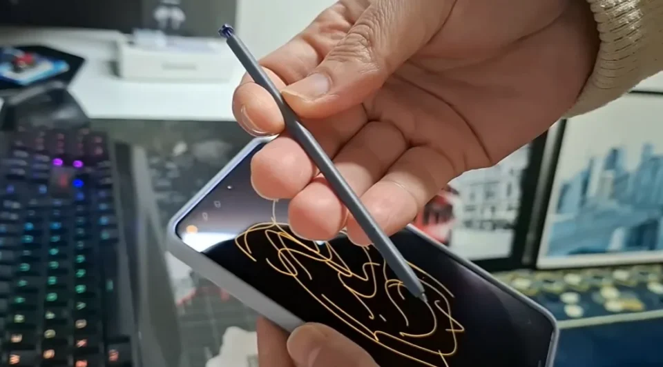 Mão segurando a caneta S Pen preta do smartphone Samsung Galaxy S26 Ultra em detalhes.