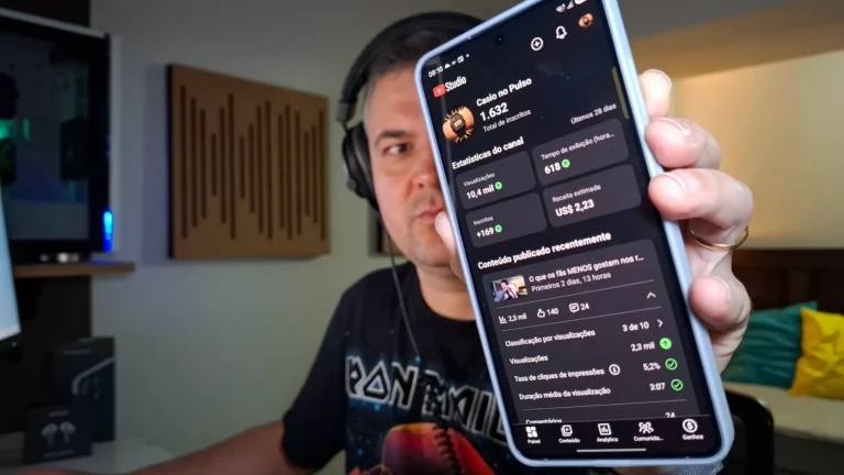 Homem mostrando a tela de um smartphone com métricas e estatísticas do canal no YouTube.