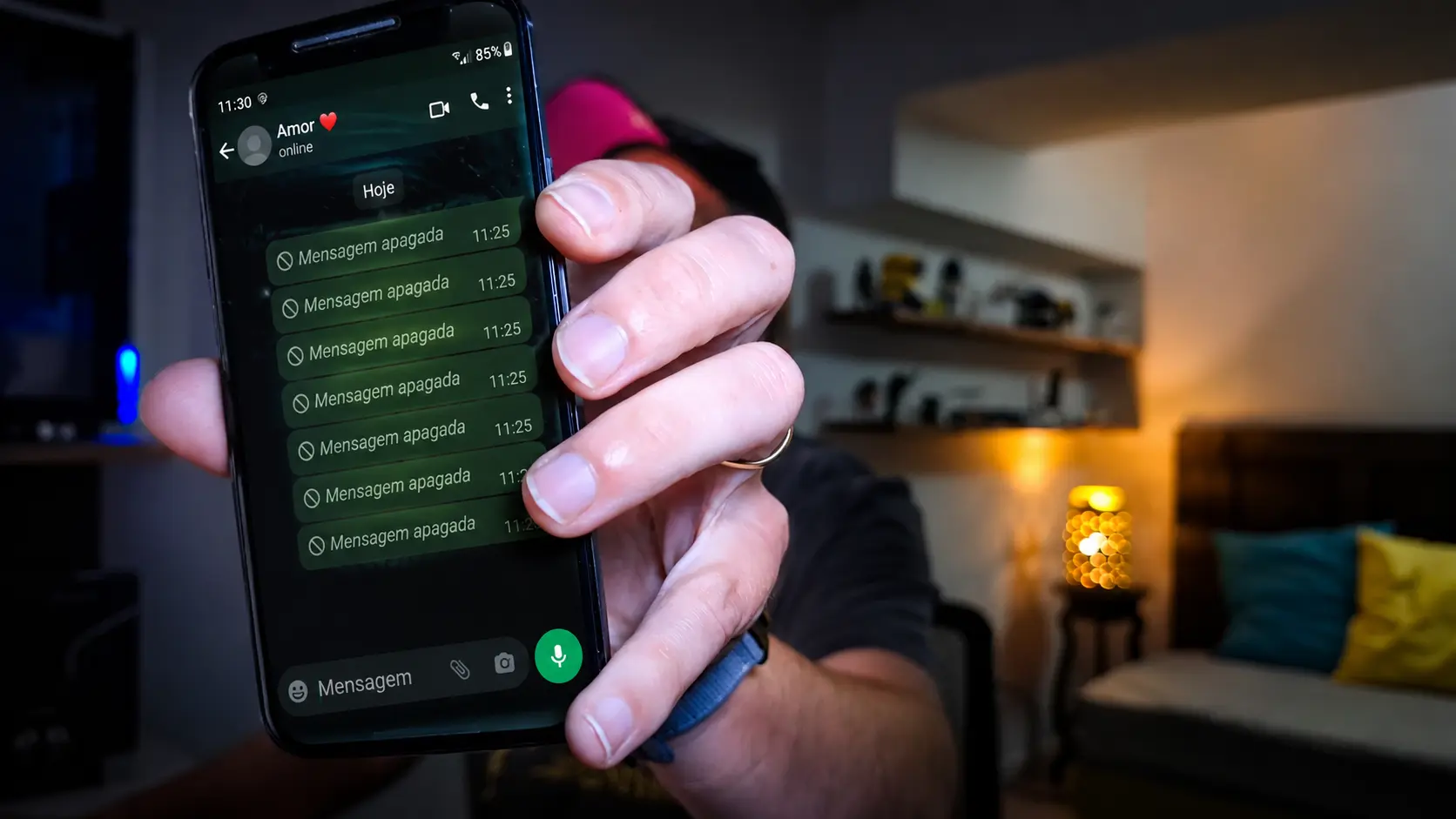 Pessoa segurando um smartphone com a tela do WhatsApp aberta em um ambiente aconchegante.