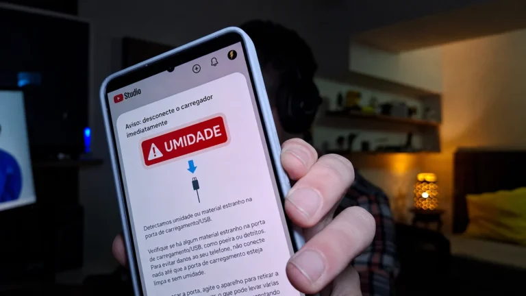 Mão segurando um celular Samsung exibindo a mensagem de aviso de umidade ou material estranho na porta de carregamento USB.