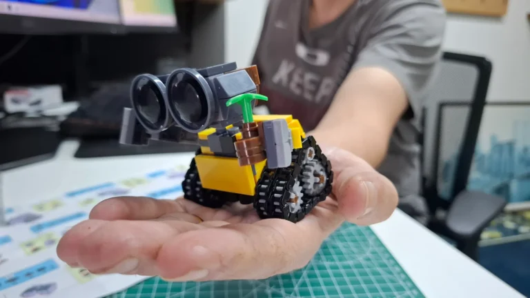 Mão segurando um mini robô WALL-E feito de blocos de montar tipo LEGO comprado no AliExpress.